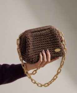 Sac à main Espresso Chic de Patrinova couleur marron chocolat porté à la main par une femme, mettant en valeur sa chaîne dorée et ma maille en crochet haut de gamme.