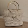 Sac à main artisanal Papillon Doré de Patrinova en crochet couleur sable avec anses circulaires rigides en métal doré et motif papillon scintillant. حقيبة يد كروشيه بلون رملي طبيعي (Sac à main en crochet couleur sable naturelle) حقيبة يد الفراشة الذهبية للمناسبات (Sac à main Papillon Doré pour événements) صناعة تقليدية تونسية فاخرة بمقبض ذهبي (Artisanat traditionnel tunisien de luxe avec poignée dorée) حقيبة سهرة تونسية راقية مصنوعة يدويا (Sac de soirée tunisien raffiné fait main)