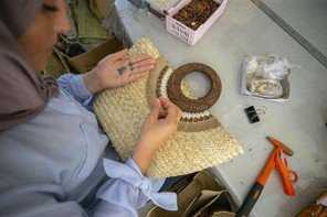 Mains d'une artisane tunisienne façonnant une pièce artisanale